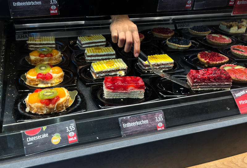 Fruit-topped tarts and cheescakes on a serving counter