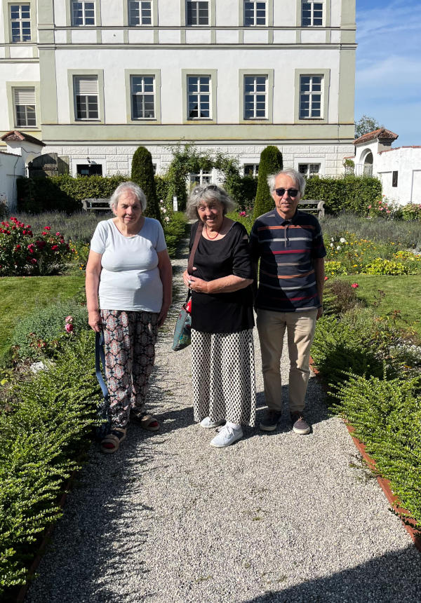 Miriam, Hansi and Martin standing in a formal garden with the while convent building in the background